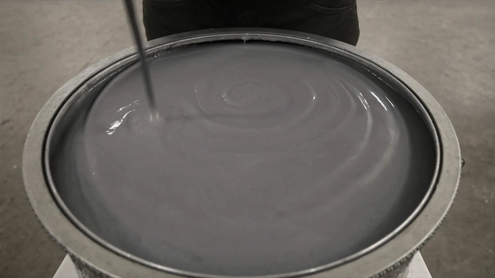 A thick grey coating in an open metal pail